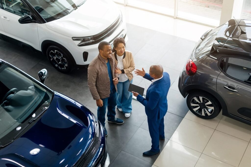 Couple discusses vehicle options with a salesman at a car dealership during purchase process