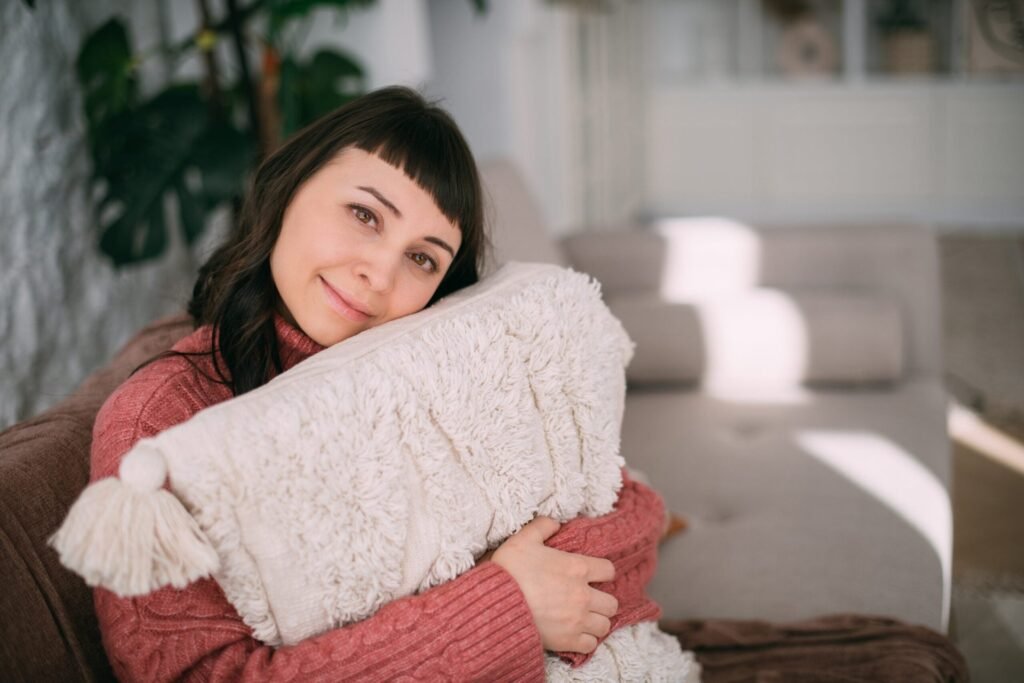 30 Tips for Staying Warm and Toasty This Winter Without Breaking the Bank woman in sweater with pillow