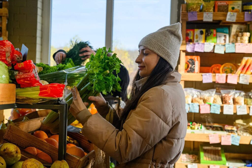 Woman in a coat and beanie shopping for fresh produce at a farmers market