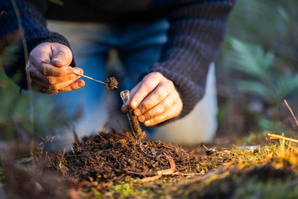 A man puts a soil sample into a vial for testing