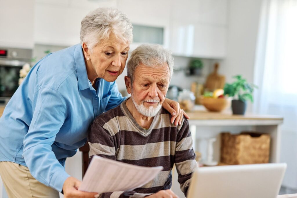 Senior couple checking bills and calculating expenses using a laptop at home