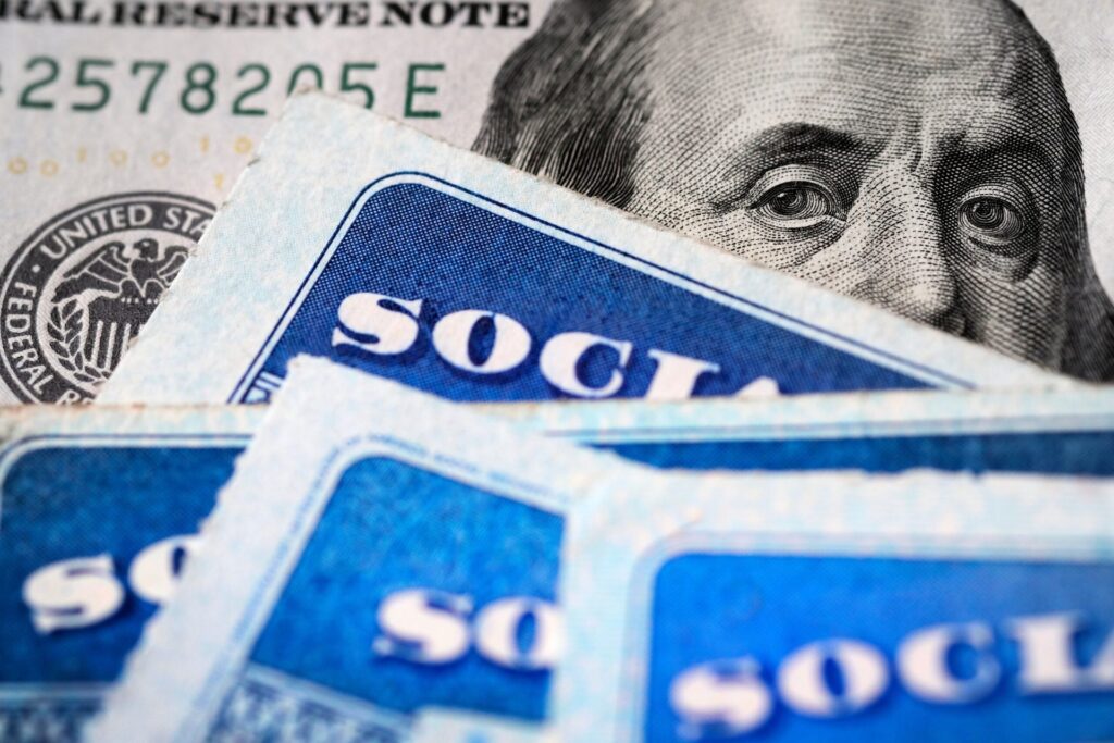 Benjamin Franklin peeking out from a $100 bill over Social Security cards