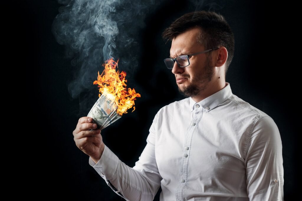 A confused man holds burning cash