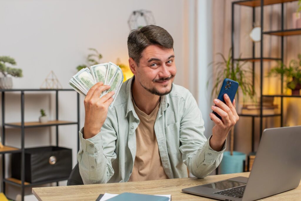 4 Financial Goals Everyone Should Have (and How to Achieve Them) Happy man holding money