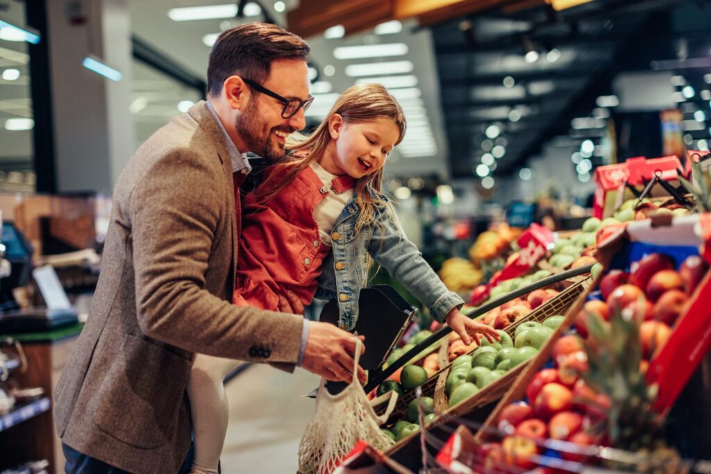 A dad and daughter shop together in the produce section.