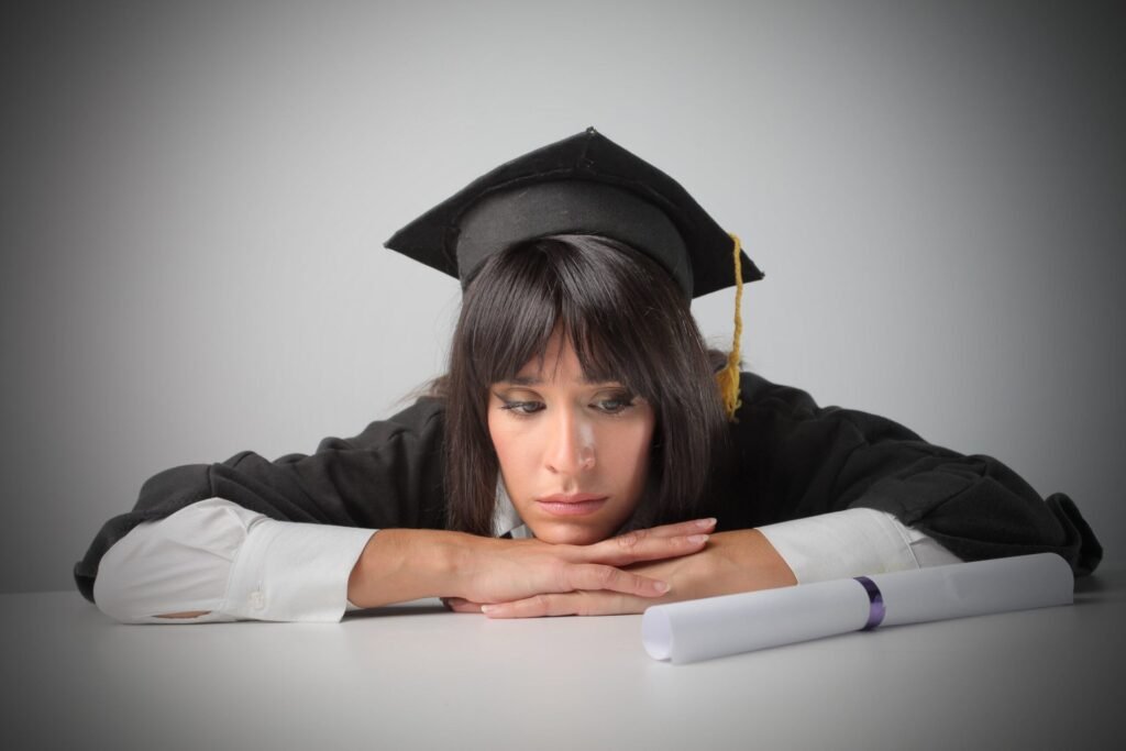 Sad college graduate looks at her diploma.