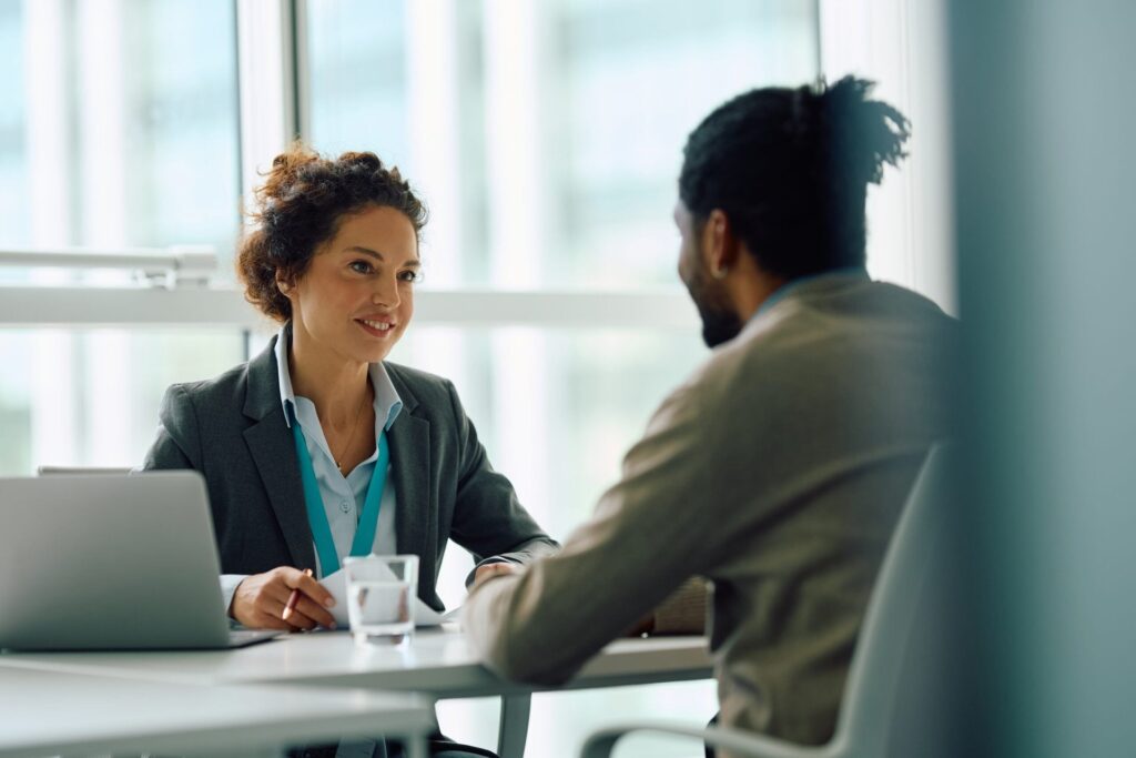 Human resource manager talking to a candidate during a job interview in an office.