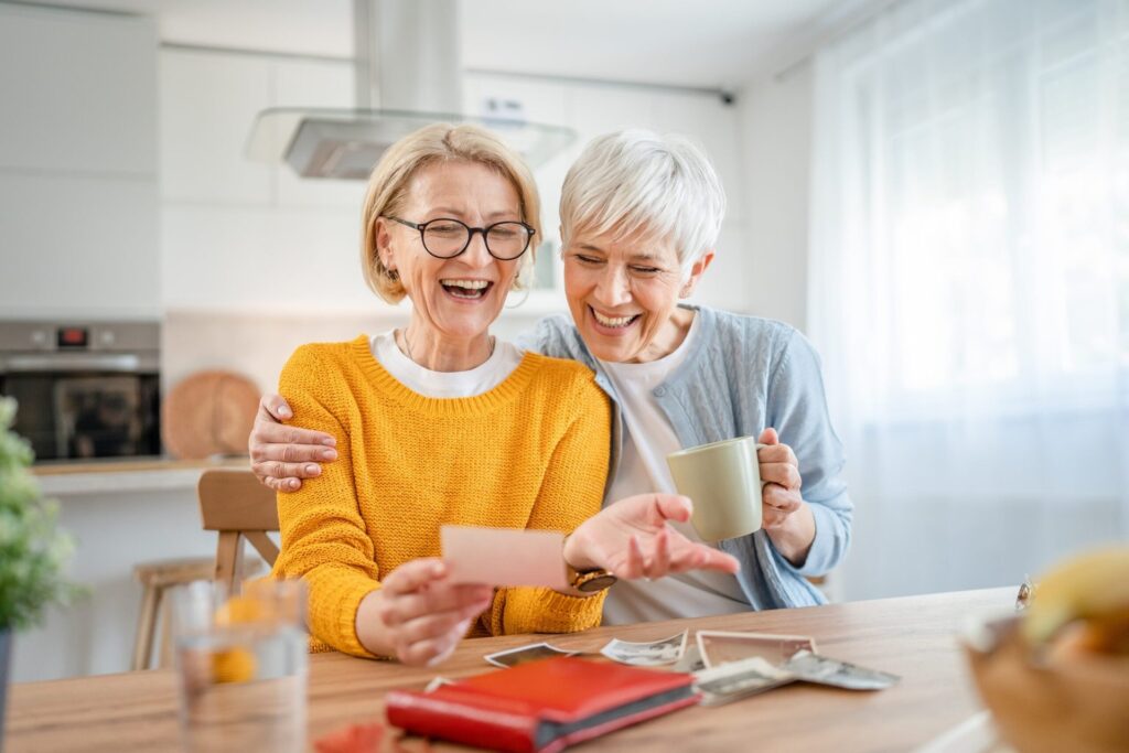 Two happy older women look at photos and remember old times
