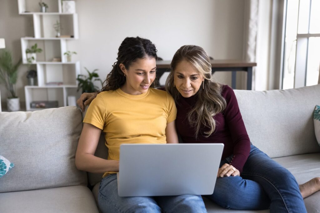 Mom and daughter look at a laptop together. Gen Z worker, overinvolved mother.