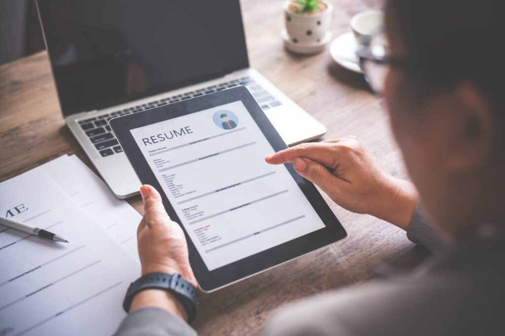 Person looking at a digital resume on a tablet while sitting at a desk in an office.