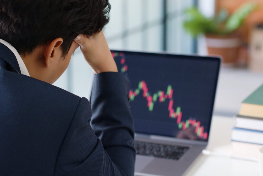 Stressed man in a suit looking at a chart of the stock market falling.